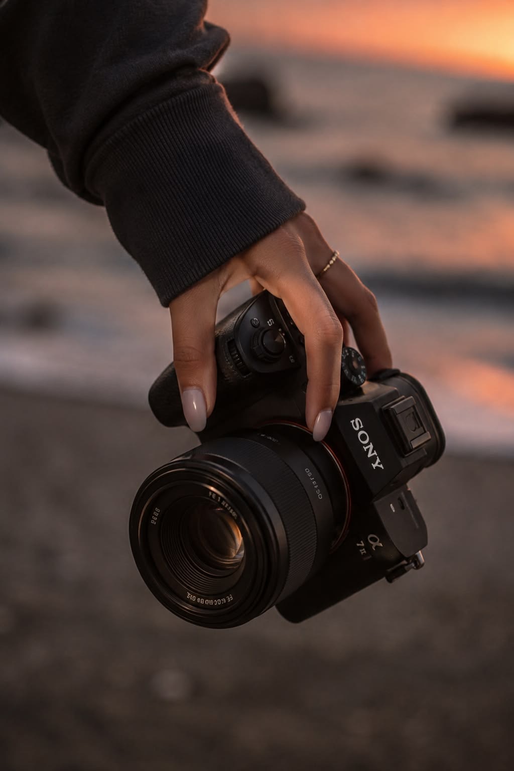 A photographer holding a Sony camera at sunset